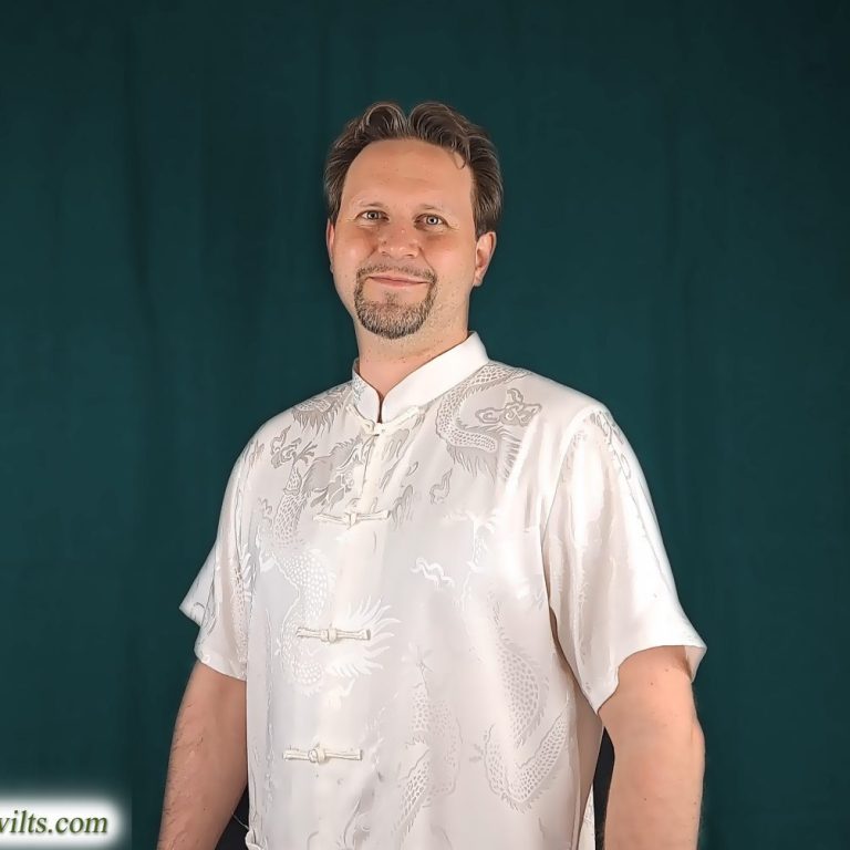 Mann in einem hellen, traditionellen Oberteil mit Innentaschen und lächelndem Gesicht.