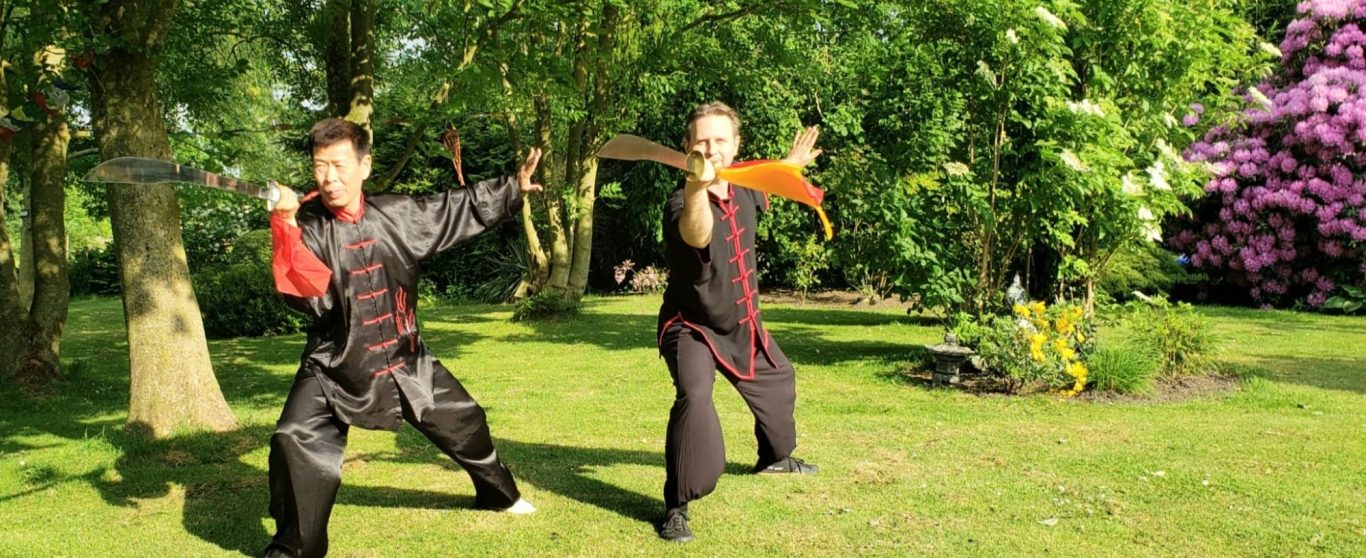 Kampfsportler in traditioneller Kleidung, bereit mit dem Schwert bei Sonnenuntergang.