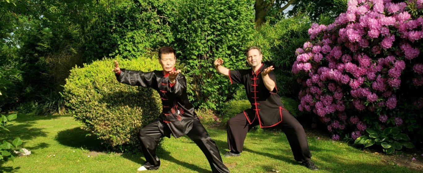 Kampfsportler in traditioneller Kleidung, bereit mit dem Schwert bei Sonnenuntergang.