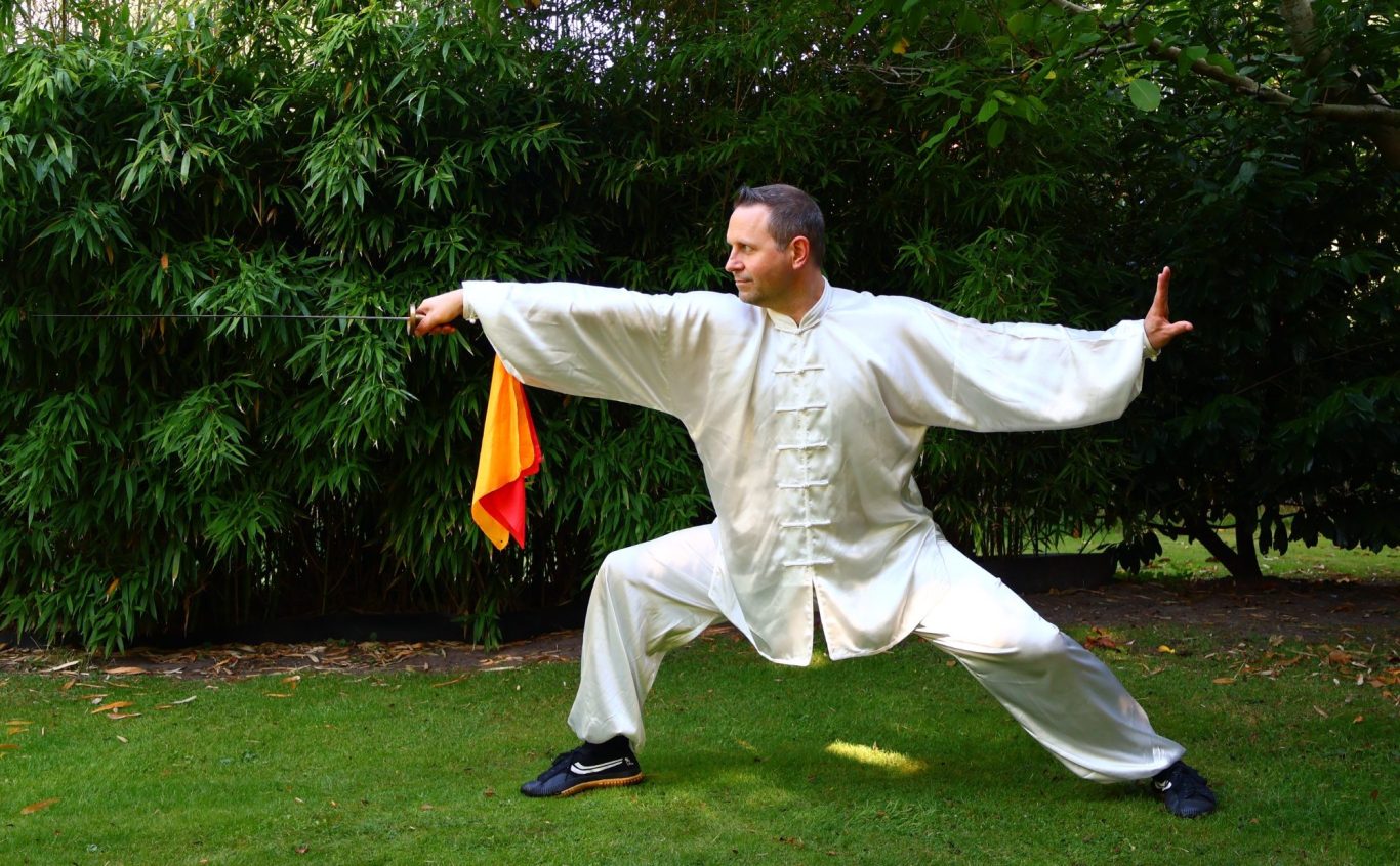Kampfsportler in traditioneller Kleidung, bereit mit dem Schwert bei Sonnenuntergang.